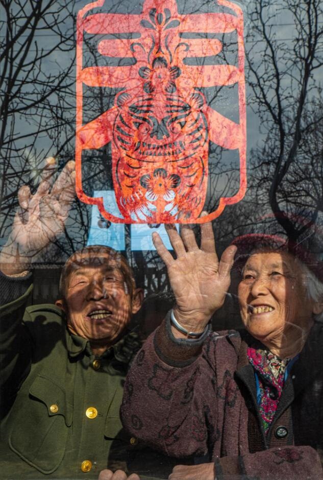 臘月里，霍州市師莊鄉(xiāng)馮南垣村村民師榮光(左)在災(zāi)后重建的新家里貼窗花。(霍州市委宣傳部供圖)
