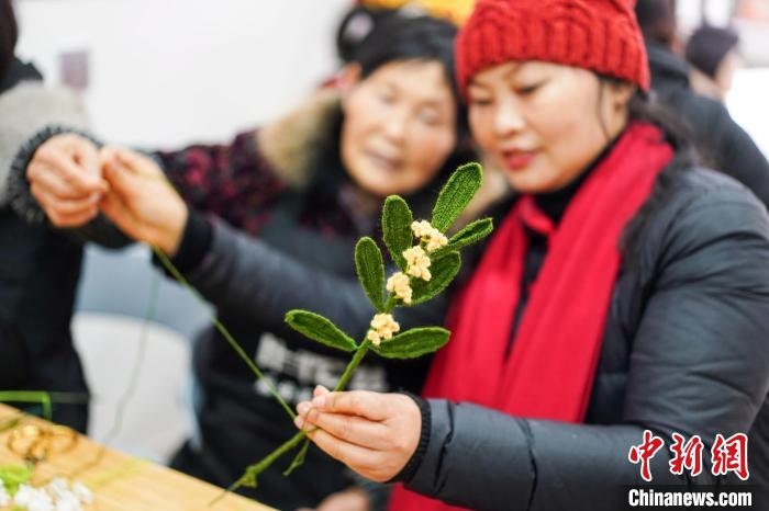 馮燕霞指導(dǎo)姐妹們鉤織月桂葉片。　古良駒 攝