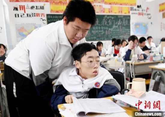 朱金祥(左)把鐘華強放到課堂座位上后，都要把他擺正好，確認(rèn)安全后才回到自己的座位上。 卓忠偉 攝