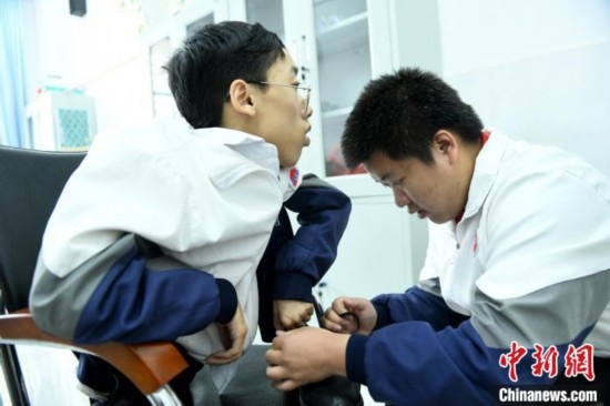 江西省南康中學(xué)北校區(qū)的高三學(xué)生朱金祥(右)正在給鐘華強(左)系好鞋帶。 卓忠偉 攝