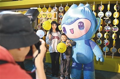 5月7日，在浙江省杭州市湖濱步行街“3D笑臉墻”前，攝影師為游客與杭州亞運(yùn)會(huì)吉祥物之一“宸宸”拍攝合影。