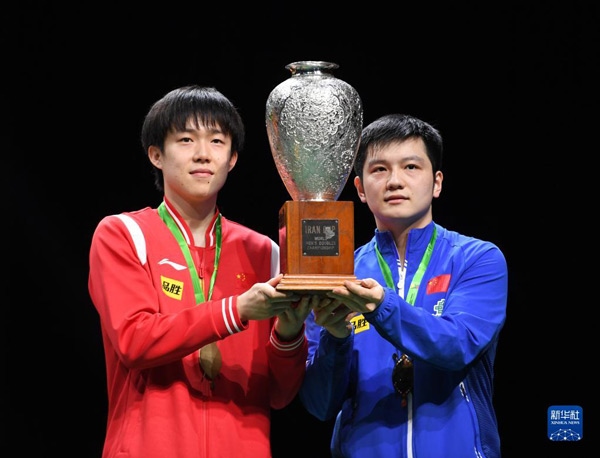 5月27日，樊振東（右）/王楚欽在頒獎(jiǎng)儀式上高舉獎(jiǎng)杯慶祝。當(dāng)日，在南非德班進(jìn)行的2023年世界乒乓球錦標(biāo)賽男雙決賽中，中國(guó)組合樊振東/王楚欽以3比0戰(zhàn)勝韓國(guó)組合張禹珍/林鐘勛，奪得冠軍。新華社記者 李亞輝攝