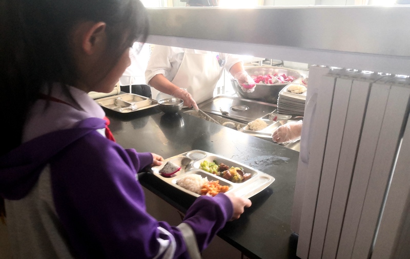 伊金霍洛旗第一小學(xué)學(xué)生正在打飯，今天的飯菜是三菜一湯外加水果，學(xué)生可以多次盛取，吃飽為止。人民網(wǎng)記者 孫博洋攝