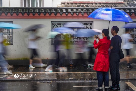 6月7日，在浙江省2023年普通高校招生考試鎮(zhèn)海中學(xué)考點(diǎn)，家長(zhǎng)冒雨目送子女進(jìn)入考場(chǎng)。人民網(wǎng) 章勇濤攝