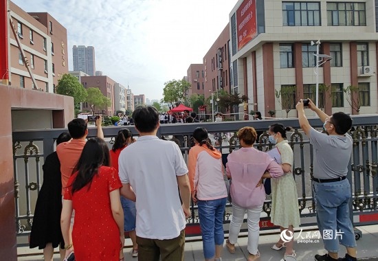 6月7日，武漢市第三中學(xué)考點(diǎn)，考生進(jìn)場(chǎng)后，家長(zhǎng)在柵欄外用手機(jī)拍攝自己的孩子。人民網(wǎng)記者 郭婷婷攝