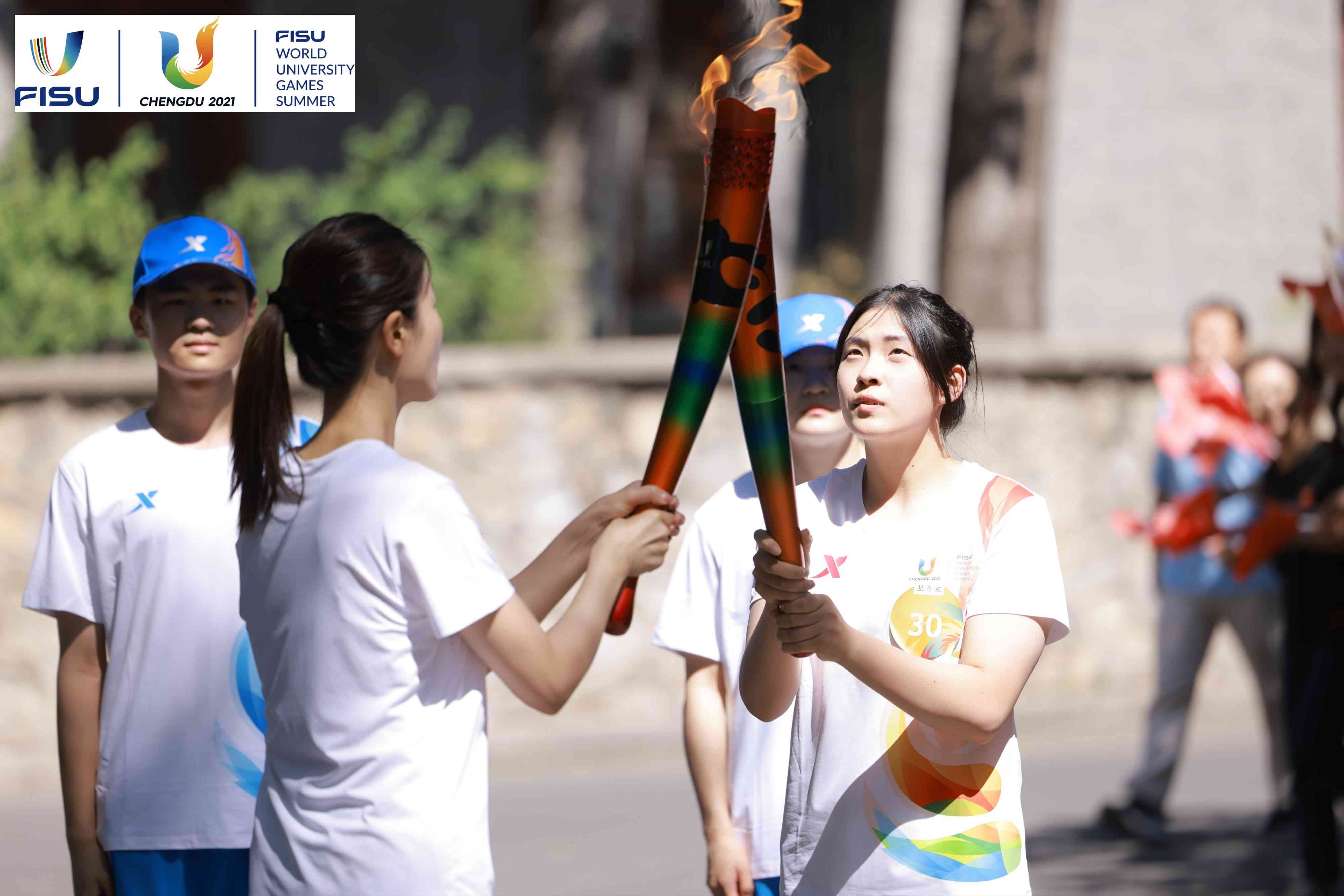 兩名大運會火炬手進行火炬?zhèn)鬟f。 圖片來源：成都大運會執(zhí)委會供圖