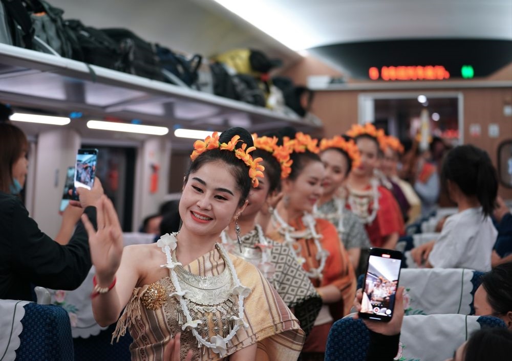 2023年4月13日，老撾工作人員在D887次國際旅客列車上表演。當(dāng)日，中老鐵路從中國昆明南站、老撾萬象站雙向?qū)﹂_D887次和D888次國際旅客列車，兩地乘火車可當(dāng)日通達(dá)。中老鐵路是高質(zhì)量共建“一帶一路”的標(biāo)志性工程。新華社記者 邢廣利 攝
