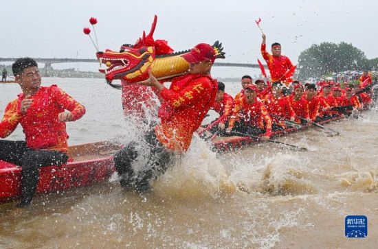 6月22日，在湖南省岳陽市湘陰縣湘江臨資口水域，參加龍舟賽的隊員接“龍頭”下水。