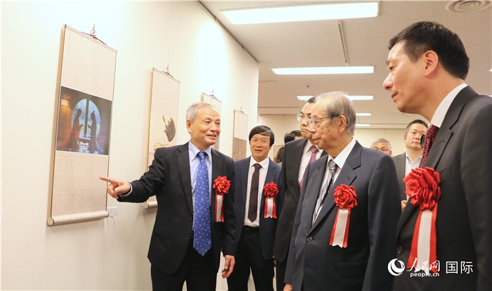 “湖州印象”攝影展主創(chuàng)、世界華人攝影協(xié)會副會長馮學敏向吳江浩大使、福田康夫前首相等嘉賓介紹展出作品。（人民網 許可攝）