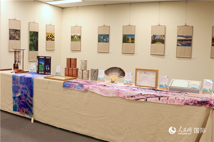 現(xiàn)場展出的馮學敏攝影作品與湖州市特色工藝品。（人民網 許可攝）