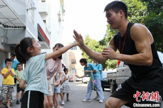 圖為大學(xué)生志愿者在組織孩子們參加體育健身活動。廖光福 攝
