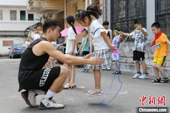 圖為大學(xué)生志愿者在教孩子們學(xué)跳繩。廖光福 攝