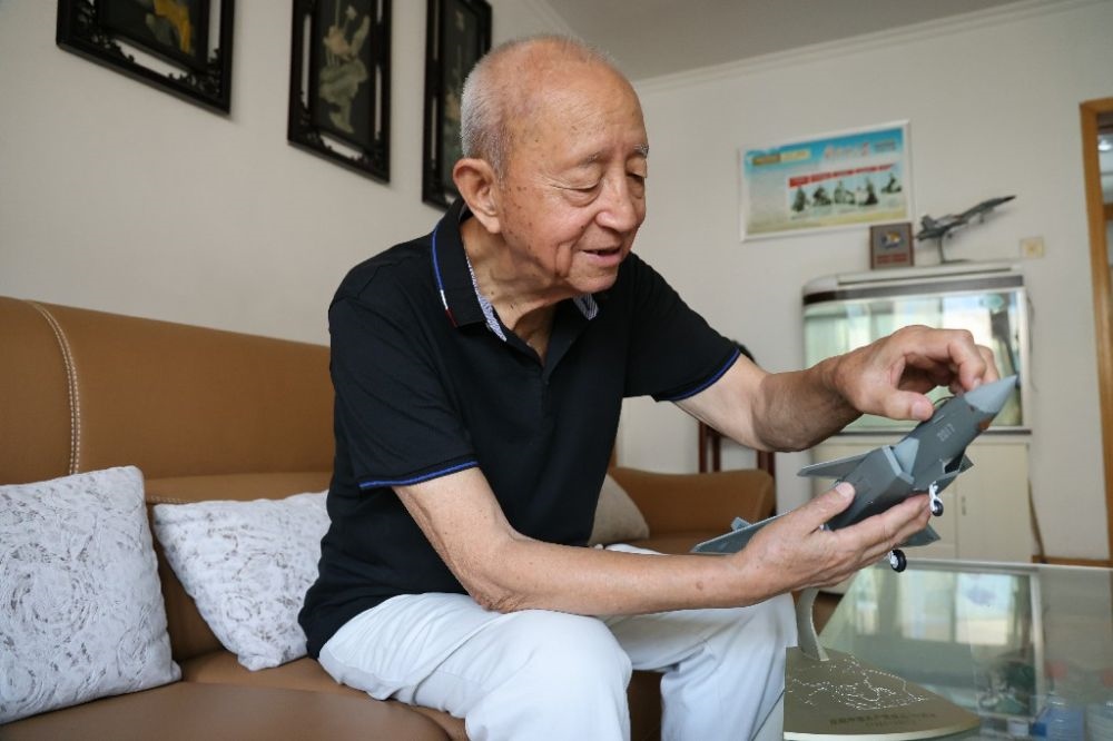 ↑2023年7月24日，新中國(guó)第一代飛行員陶偉在家中擦拭殲-20飛機(jī)模型。新華社發(fā)（張瑞 攝）
