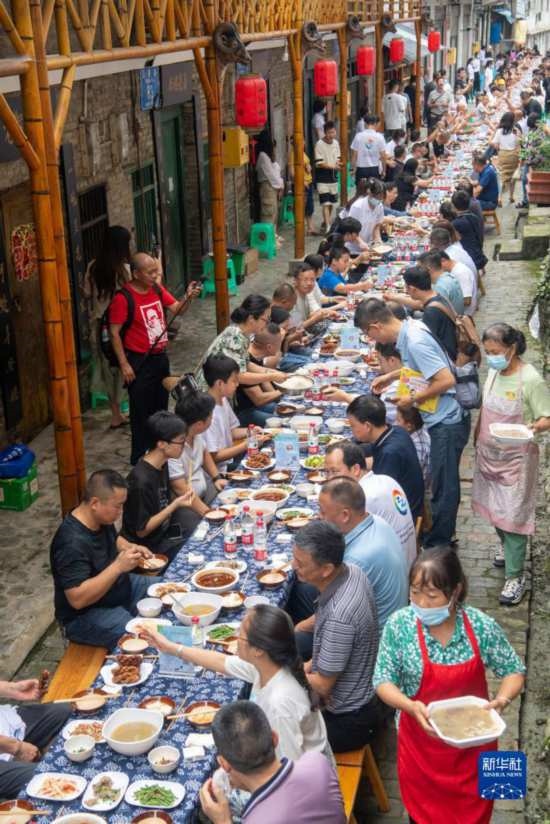 7月29日，在重慶市綦江區(qū)安穩(wěn)鎮(zhèn)，人們在“苗家伏羊節(jié)”上吃長桌宴。新華社記者 唐奕 攝
