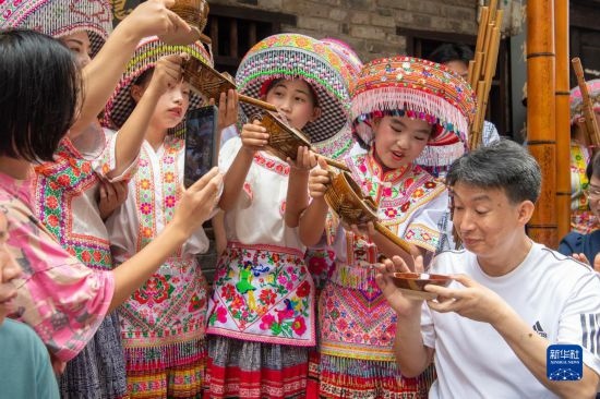 7月29日，在重慶市綦江區(qū)安穩(wěn)鎮(zhèn)，當(dāng)?shù)鼐用裨凇懊缂曳蚬?jié)”上用傳統(tǒng)習(xí)俗向游客表達(dá)祝福。新華社記者 唐奕 攝