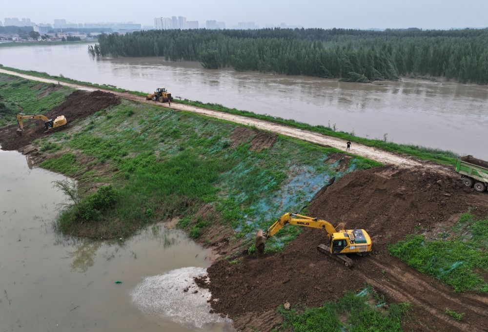 工人操作機械在白溝河左堤白溝新城高橋村段進行除險加固作業(yè)（8月4日攝，無人機照片）。新華社記者 朱旭東 攝