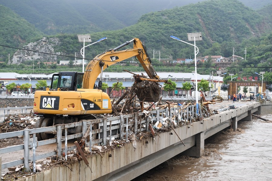 8月1日，在北京市門頭溝區(qū)水峪嘴村村口，一臺(tái)挖掘機(jī)在清理阻斷橋梁交通的雜物。目前該條道路已經(jīng)疏通完成。新華社記者 鞠煥宗 攝