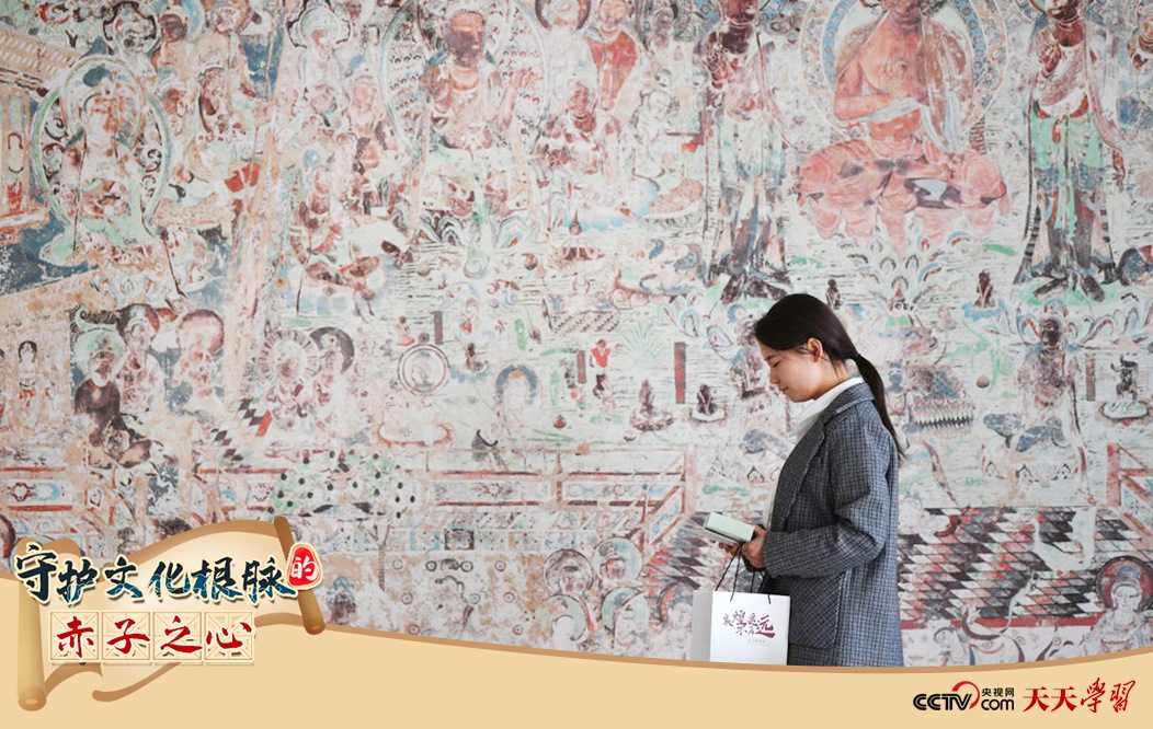 2023年4月25日，敦煌研究院文物數(shù)字化保護團隊創(chuàng)意營銷人員廖雪婷從一幅高保真復制壁畫前走過。