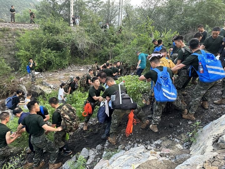 8月2日，Z180次受困列車的旅客在武警北京總隊機動第三支隊官兵的幫助下徒步前往轉(zhuǎn)運客車（手機照片）。新華社記者 王艷剛 攝