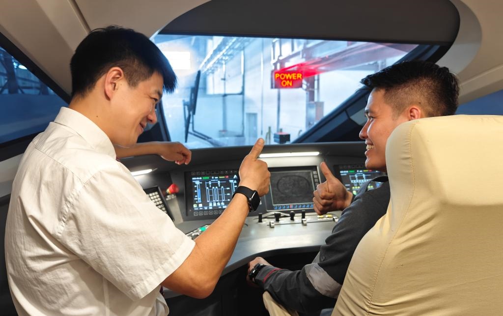 8月25日，在印度尼西亞萬隆的雅萬高鐵德卡魯爾動車所內，中國師傅穆振（左）在向印尼火車司機塞蒂亞萬講解動車組出庫前的上電作業(yè)。