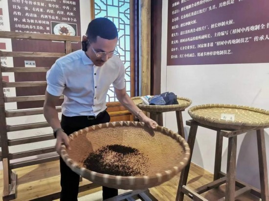 2023“一帶一路”媒體合作論壇聯(lián)合采訪團團員在非遺文化展示館體驗中藥炮制技藝。（本報記者 黃超攝）