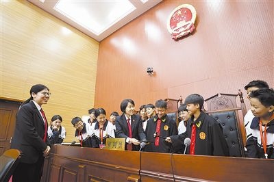 圖③：同學(xué)們穿法袍、敲法槌，爭做“小法官”。
