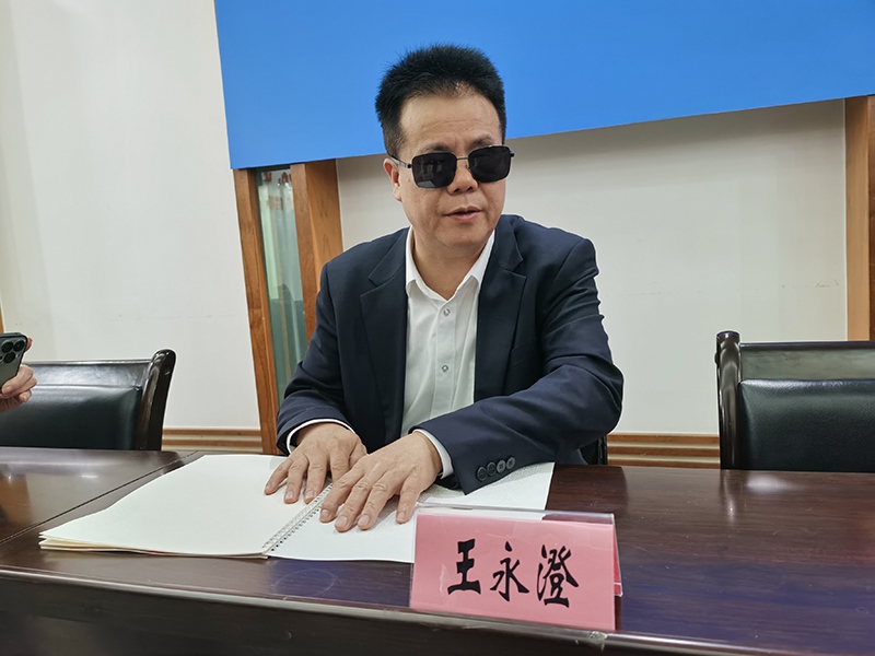 全國(guó)人大代表王永澄正在閱讀盲文版代表建議答復(fù)。本報(bào)記者 張 璁?dāng)z