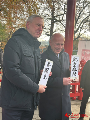 柏林市長韋格納（右）、動物園監(jiān)事會主席布魯克曼（左）手持中國文化中心工作人員現(xiàn)場手書的中文名字。人民網(wǎng)記者 徐馨攝
