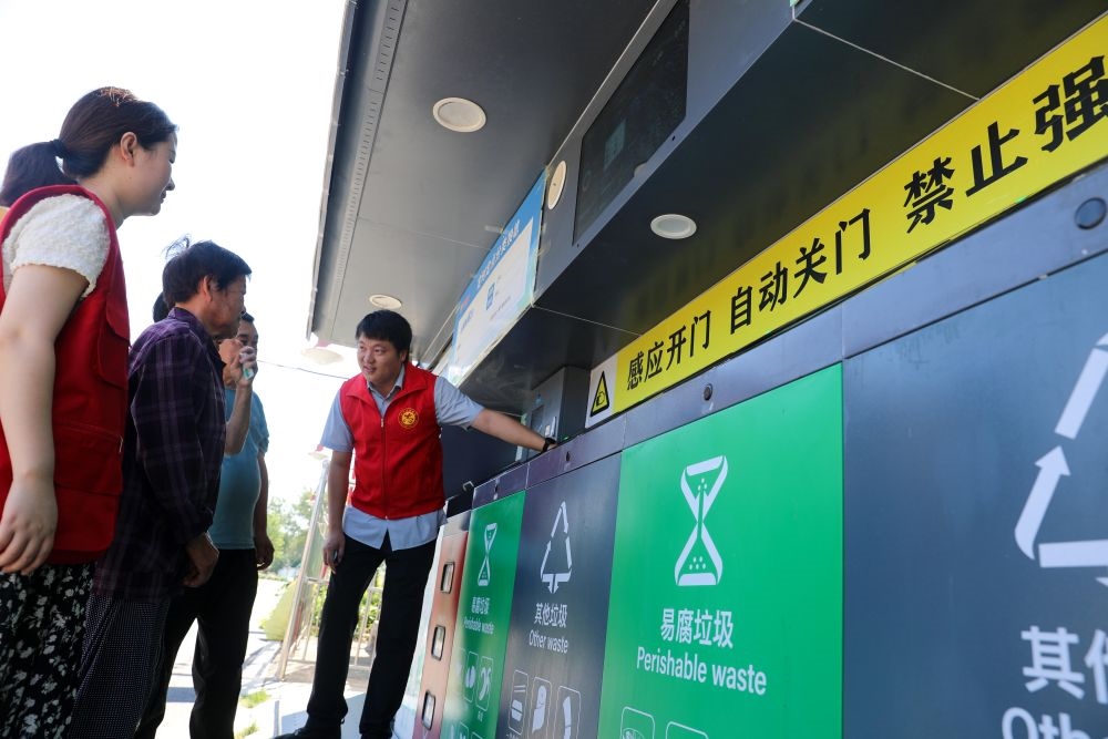 在安徽省合肥市長(zhǎng)豐縣莊墓鎮(zhèn)棗林社區(qū)，志愿者指導(dǎo)居民使用智能垃圾分類(lèi)回收設(shè)備（2023年9月1日攝）。新華社記者 曹力 攝
