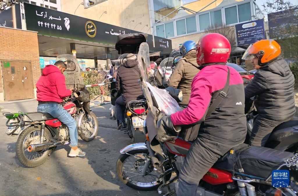 12月18日，摩托車(chē)在伊朗首都德黑蘭的一家加油站外等待加油。新華社記者 沙達(dá)提 攝