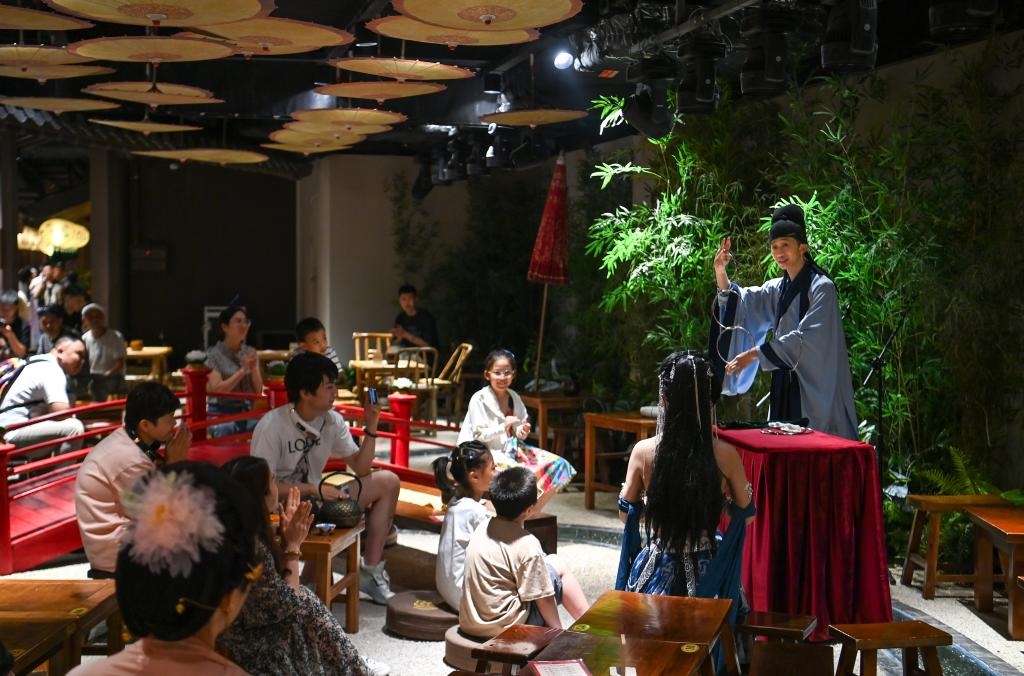 游客在長(zhǎng)安十二時(shí)辰主題街區(qū)觀看唐風(fēng)演藝《大唐曲藝》。新華社記者鄒競(jìng)一 攝