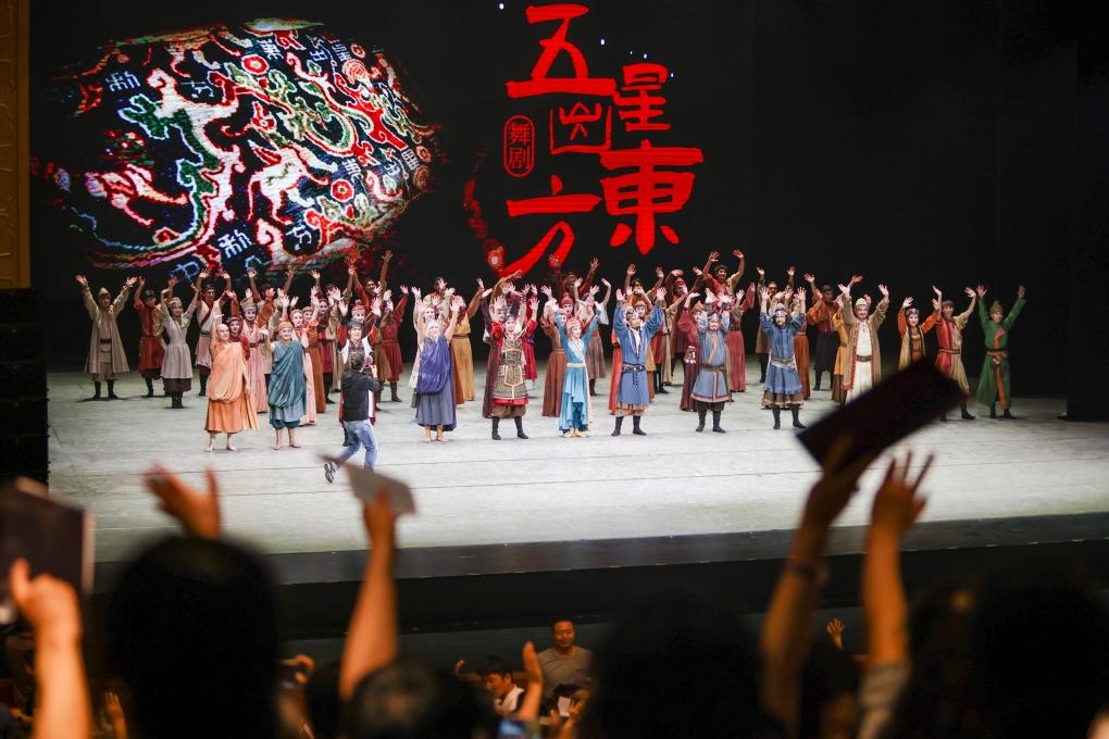 2023年7月31日，新疆和田地區(qū)新玉歌舞團(tuán)在烏魯木齊京劇院演出舞劇《五星出東方》后和觀眾互相揮手致意。這場演出是第六屆中國新疆國際民族舞蹈節(jié)的參演劇目之一，曾榮獲國家“文華獎”等。新華社記者 郝昭 攝