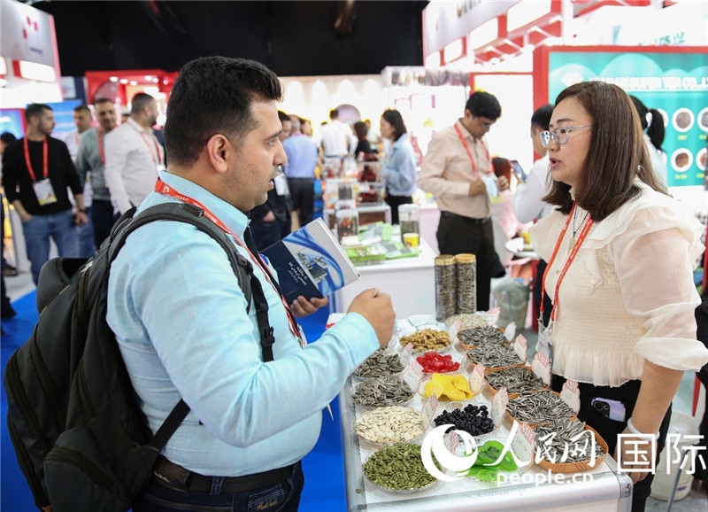 圖為一家中國(guó)干果參展企業(yè)代表與采購(gòu)商洽談。人民網(wǎng) 塔里克·易卜拉欣攝