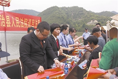 法院干警及相關(guān)部門工作人員對(duì)群眾進(jìn)行生態(tài)環(huán)境保護(hù)普法教育。