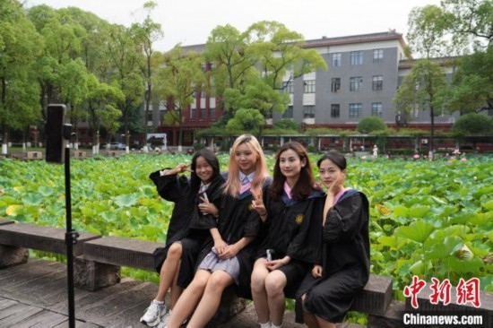 6月19日，時值一年畢業(yè)季，四川大學望江校區(qū)荷花池里的荷花盛開，成為了畢業(yè)生們的打卡圣地，吸引了眾多畢業(yè)生拍照留念。圖為畢業(yè)生在荷花池邊拍照留念。中新社記者 安源 攝