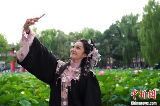 6月19日，時值一年畢業(yè)季，四川大學望江校區(qū)荷花池里的荷花盛開，成為了畢業(yè)生們的打卡圣地，吸引了眾多畢業(yè)生拍照留念。圖為畢業(yè)生在荷花池邊拍照留念。中新社記者 安源 攝