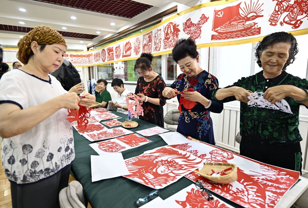 6月19日，長城花園社區(qū)居民在社區(qū)“才藝堂”制作剪紙。