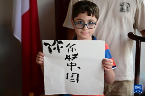 7月4日，在馬耳他桑塔露琪亞市的中國古典園林“靜園”，一名男孩展示他的書法作品。新華社發(fā)（喬納森·博格 攝）