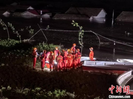  7月6日凌晨3時，在湖南岳陽華容縣團(tuán)洲垸洞庭湖一線堤防，救援人員剛剛完成一次救援任務(wù)，遠(yuǎn)處是被淹的民房。中新社記者 白祖偕 攝