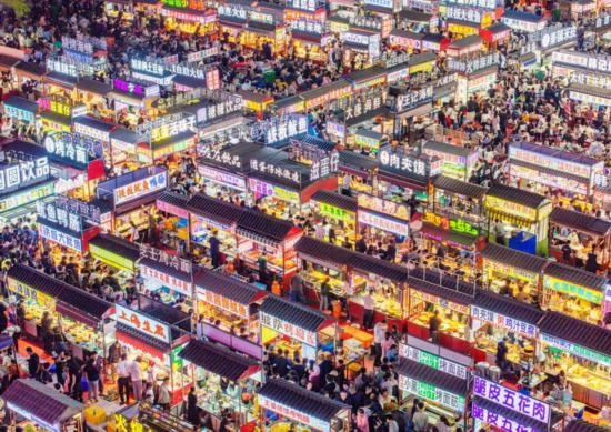2024年4月21日，人們?cè)诤颖笔≌h小商品夜市品嘗美食（無(wú)人機(jī)照片）。新華社發(fā)（武志偉 攝）