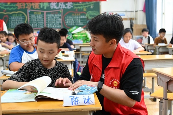 鄭州市二七區(qū)暑托班的志愿者輔導(dǎo)孩子寫(xiě)作業(yè)。人民網(wǎng)記者王玉興攝