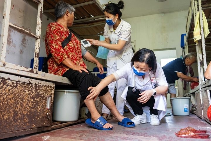 2024年7月30日，在湖南省湘潭縣河口中學(xué)安置點，醫(yī)務(wù)人員為受洪水影響而轉(zhuǎn)移安置的群眾檢查身體。 新華社記者 陳思汗 攝