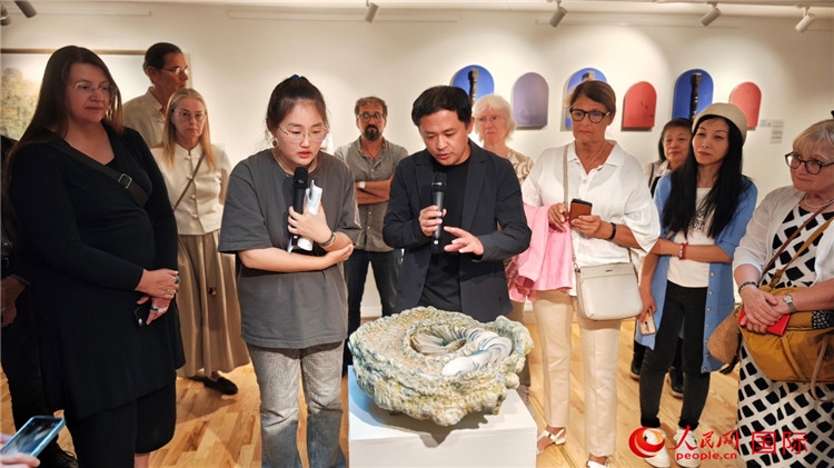 參展人、景德鎮(zhèn)陶瓷大學(xué)設(shè)計(jì)藝術(shù)學(xué)院副院長(zhǎng)余劍峰（中）向來(lái)賓介紹參展作品。人民網(wǎng)記者 殷淼攝
