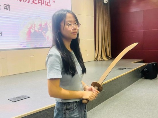 圖為南開大學(xué)社會實(shí)踐隊(duì)學(xué)生代表呼月紅在學(xué)術(shù)交流活動現(xiàn)場，展示河間調(diào)研行中獲贈的一戰(zhàn)華工蔡世春曾使用過的一把大刀。林卓瑋 攝