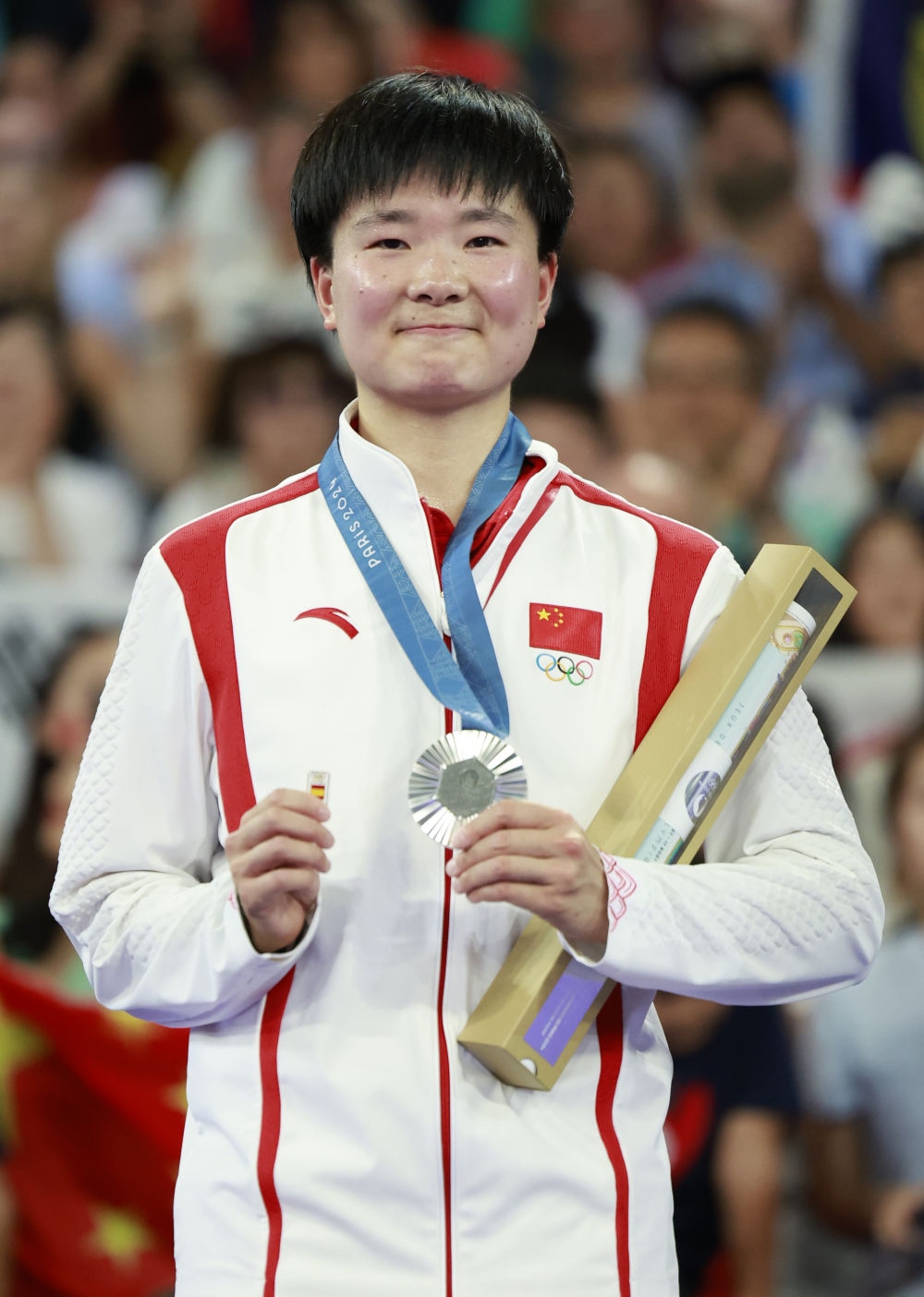 巴黎奧運會羽毛球女子單打亞軍、中國選手何冰嬌在頒獎儀式上一手握著銀牌，一手握著西班牙奧委會徽章（2024年8月5日攝）。新華社記者 任正來 攝