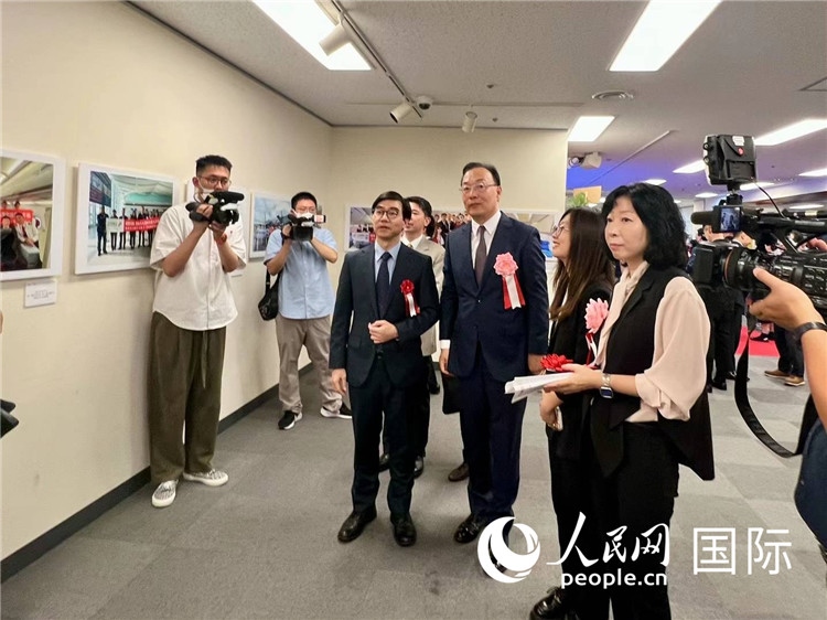 中國(guó)國(guó)際航空日韓地區(qū)支社支社長(zhǎng)馮力為中國(guó)駐日本大使館臨時(shí)代辦施泳等嘉賓介紹展出圖片。人民網(wǎng) 許可攝