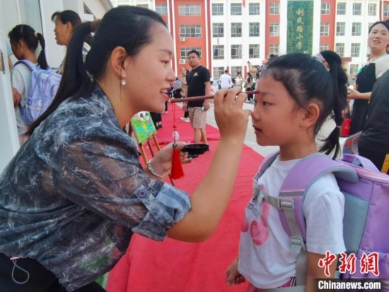 圖為衡水市利民路小學，老師為學生點朱砂痣，寓意開啟智慧。張松 攝