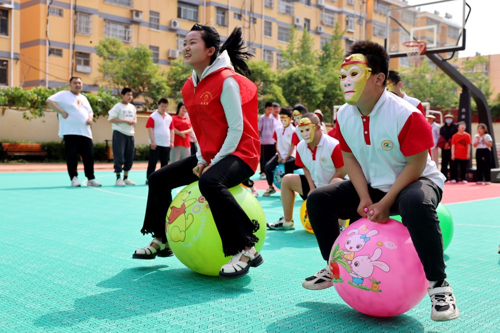 2024年5月17日，在山東省棗莊市市中區(qū)特殊教育中心，青年志愿者與智力障礙學(xué)生一起做游戲。新華社發(fā)（孫中喆攝）