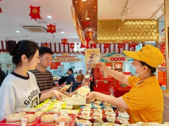 北京稻香村一家門店內(nèi)，售貨員向顧客展示新上市的月餅禮盒。（受訪者供圖）