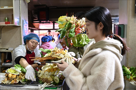 游客挑選好麻辣燙菜品后排隊等待加工。新華社記者 范培珅 攝